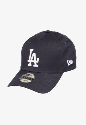 Navy blue baseball cap made of fabric, featuring a raised white "LA" logo on the front. Adjustable strap at the back. Classic curved brim design.