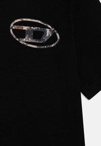 Čierne bavlnené tričko s textúrovaným grafickým logom v šedých a modrých odtieňoch, umiestnené centrálne na hrudi. Krátke rukávy, klasický strih.