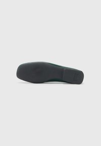 Sola de sapato verde em camurça com um solado de borracha preta texturizada, apresentando um salto bloco e uma borda superior lisa. Design simples sem acentos visíveis.