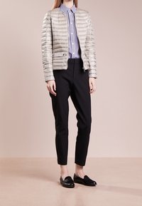 Light grey puffer jacket, ribbed texture, paired with a striped button-up shirt and black tapered pants, completed with black loafers.