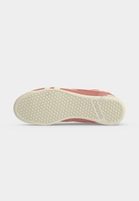 Semelle d'une basket rose avec un motif en nid d'abeille et logo Reebok sur une semelle blanche, vue de dessous sur fond blanc.