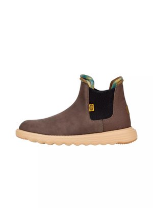 Stivaletto marrone slip-on con suola beige scanalata, pannello laterale elastico nero e fodera in tessuto a fantasia visibile al collo.
