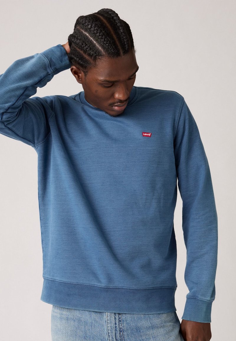Blauwe sweatshirt met ronde hals gemaakt van zachte stof, met een klein rood Levi's logo op de borst en geribbelde manchetten en onderkant.