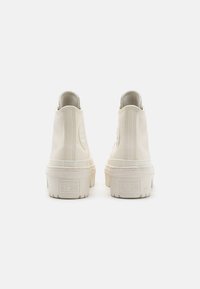 Sneakers alta in pelle off-white con superficie texturizzata. Presentano una patch con logo e una suola in gomma spessa per un'altezza aggiuntiva.
