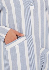 Gestreiftes Hemd in Blau und Weiß, hergestellt aus einem strukturierten Stoff, mit einer geknöpften Knopfleiste und vorderen Taschen mit kontrastierendem Besatz.