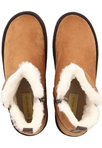 Chaussures slip-on en daim tan avec doublure en fausse fourrure blanche, présentant un design à profil bas et des semelles en caoutchouc marron. Accentué de matériel en métal.