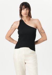 Top in cotone nero a coste con design asimmetrico a spalla unica. Realizzato in tessuto morbido, presenta una texture liscia e un orlo leggermente curvo.
