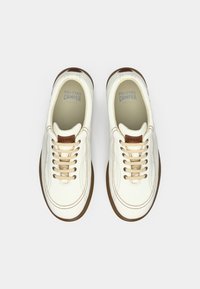 Λευκά δερμάτινα αθλητικά παπούτσια με μπεζ κορδόνια, στρογγυλή μύτη και καφέ λαστιχένιες σόλες. Λογότυπο "Camper" χαραγμένο στη γλώσσα. Ραφές με υφή.