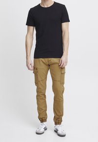 Svart t-shirt med kort ärm kombinerad med cargobyxor i khaki. Byxorna har sidofickor och elastiska muddar, med en smidig textur.