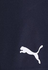 Pantalones cortos deportivos azul marino de tela suave, con un logotipo blanco de Puma que representa a un gato saltando en el lado inferior izquierdo.
