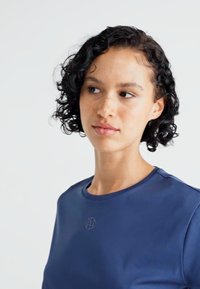 Marineblauw sportshirt met een ronde hals en korte mouwen, voorzien van een subtiel logo op de borst en een gladde, strakke textuur.