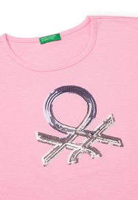 Růžové bavlněné tričko s lesklým, barevným designem z flitrů ve tvaru symbolu, s kulatým výstřihem a zelenou značkovou etikou.