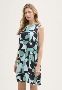 Mouwloze jurk met een zwarte basis met abstracte vormen in turquoise, wit en donkergroen. Lichtgewicht stof met een gladde textuur.