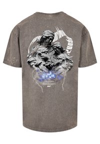 Grå oversized t-shirt med et hævet grafisk motiv af to statuer mod en stiliseret baggrund med lyn og røg, med tekst nedenfor.