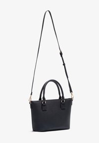 Sac à main en cuir noir avec deux poignées supérieures et une longue bandoulière réglable, présenté sur un fond blanc.