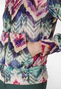 Giacca zip-up colorata con un motivo astratto nei toni vivaci di rosa, viola e verde. Include tasche laterali e polsini a coste.