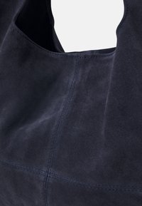 Navy blue suede handbag with a smooth texture, rounded top, and stitched detailing. Features a spacious opening for easy access.