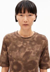 Brown, short-sleeved shirt with a textured, mottled pattern. Round neckline and loose fit. Material appears lightweight and breathable.