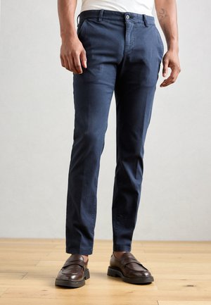 Navy blue chinos made of cotton, featuring a straight-leg cut and subtle front pockets, paired with brown leather loafers.
