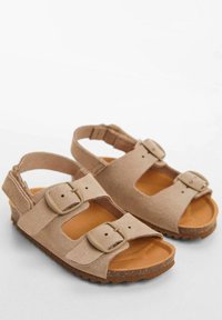 Beige mockasinsandaler med två justerbara spännen, öppen tå-design och strukturerad brun gummisula för förbättrat grepp.