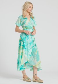 Vestido wrap en tonos aqua y verde, con mangas cortas, cinturilla ajustable y un dobladillo fluido y asimétrico con un sutil patrón de mármol.