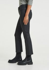 Svarta slim-fit byxor med en mjuk textur och lätt glans, matchade med kraftiga svarta ankelstövlar som har elastiska sidopaneler.