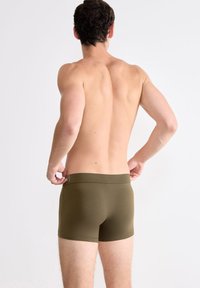 Olivgrüne Boxershorts aus weichem Stoff, mit einem glatten Bund und minimalen Nähten. Das Design ist schlank mit einer figurnahen Silhouette.