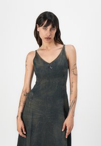 Denim obleka z V-izrezom in tankimi naramnicami, z temno modrim pranjem, oprijetim korzetom in srebrnim logotipom na prednji strani.