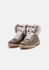 Botas de senderismo de cuero marrón con puños de piel sintética, cordones blancos, herrajes en tono dorado y suelas de goma resistentes. Acabado texturizado y cuello acolchado.