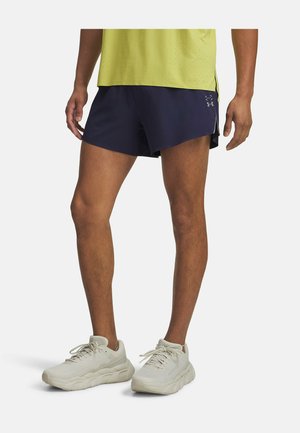 Navy athletic shorts with a lightweight design and side slits. Paired with light gray sneakers featuring a textured surface and thick sole.