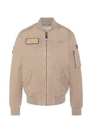 Veste bomber beige avec fermeture éclair avant, poignets et ourlet côtelés, deux poches avant, une poche zippée sur la manche, et des écussons brodés sur la poitrine et la manche.