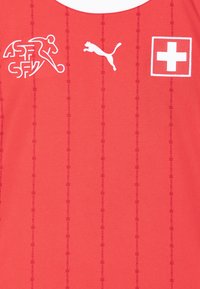 Red athletic jersey with vertical stripes, featuring a white Puma logo, a Swiss cross emblem, and an embroidered sports figure.