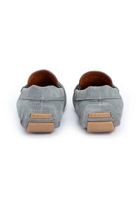 Szare zamszowe buty wsuwane z okrągłym noskiem i przeszyciami; brązowe gumowe podeszwy i teksturowane tło z akcentem logo.