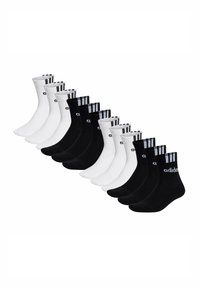 Doce pares de calcetines Adidas de media caña en blanco y negro dispuestos en colores alternos, con el logo y las tres franjas en los puños.