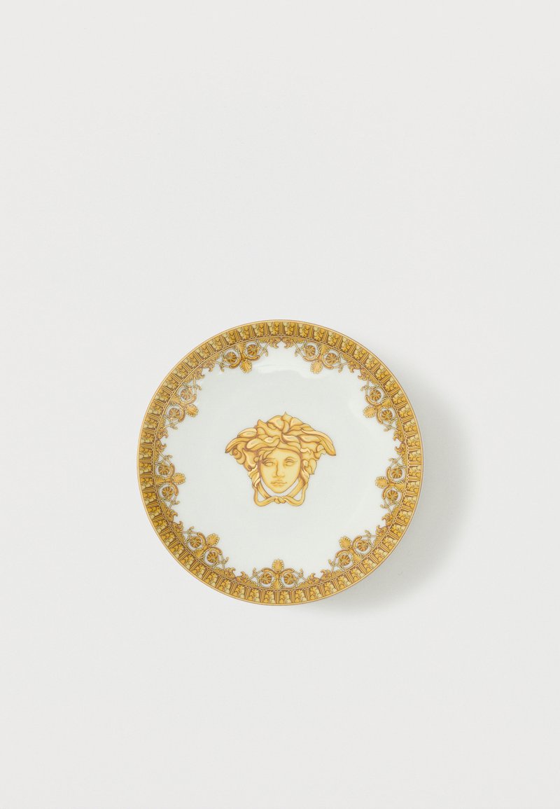 Valge portselantaldrik kuldse ornamentse serva ja keskel kuldse Medusa pea embleemiga.