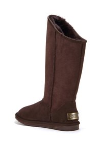 Hnědé semišové vysoké boty s měkkou umělou kožešinou uvnitř, se zaoblenou špičkou a dekoračním kovovým logem na patě.