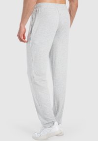 Hellgraue Sweatpants mit schmal zulaufendem Bein, elastischem Bund, Seitentaschen und einem kleinen Logodetail an der linken Seitennaht.