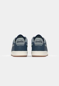 Navy blue sneakers with gray accents, textured rubber sole, soft fabric upper, and logo on heel. Low-profile design with padded collar.