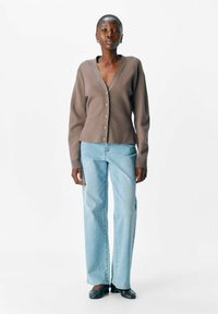 Brun, uldblandet cardigan med V-hals, lange ærmer og knapper foran, parret med lyseblå lige ben jeans og sorte sko.