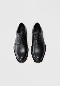 Scarpe in pelle nera con lacci, dalla finitura liscia, punta tonda, pannello laterale testurizzato a contrasto e suola piatta in gomma.