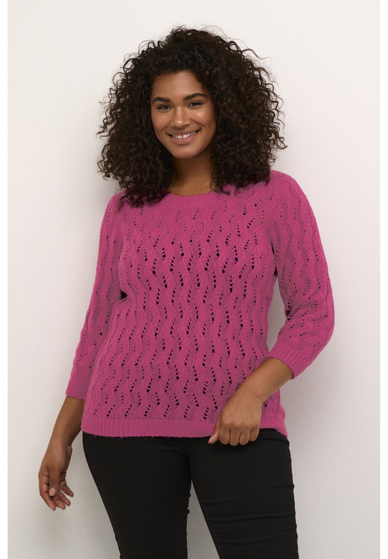 Maglione rosa in pizzo lavorato a maglia con scollatura rotonda e maniche a tre quarti, caratterizzato da un motivo a onda e polsini e bordo a coste.
