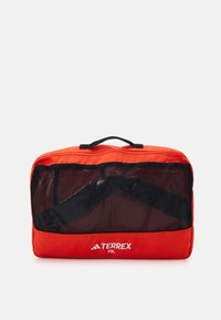 Röd 70L Terrex-väska med ett nätpanel fram, svarta accenter och ett handtag upptill. Robust material med en rektangulär form för enkel förvaring.