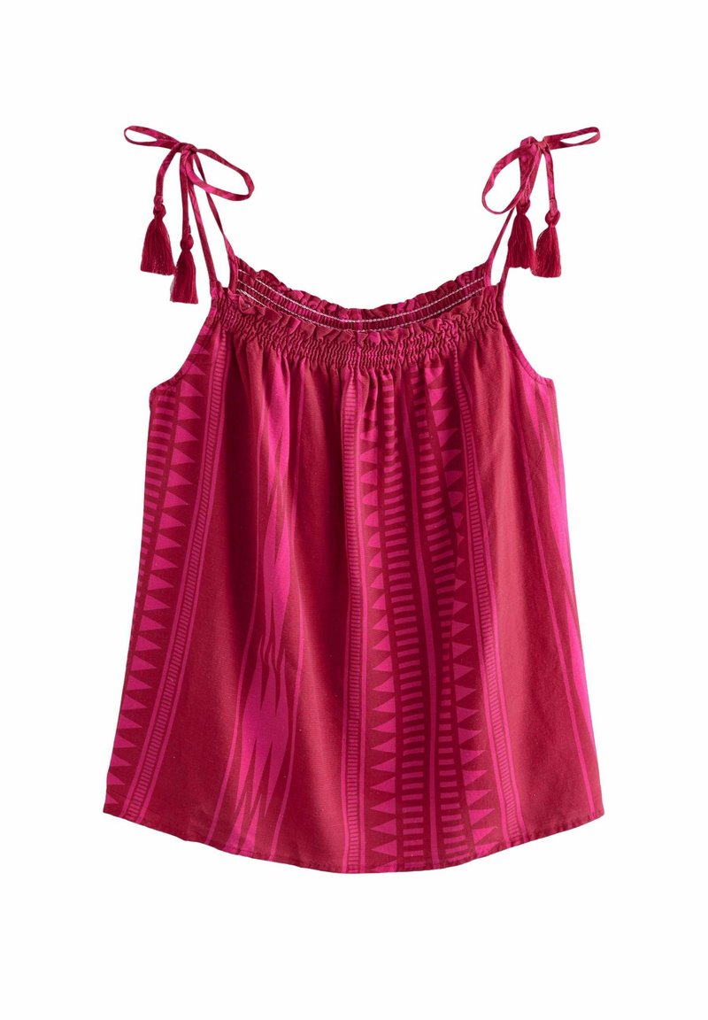 Top sans manches rose avec un smockage froncé au niveau du col, des bretelles à nouer ajustables et des motifs tribaux géométriques dans des nuances de rose plus foncé.