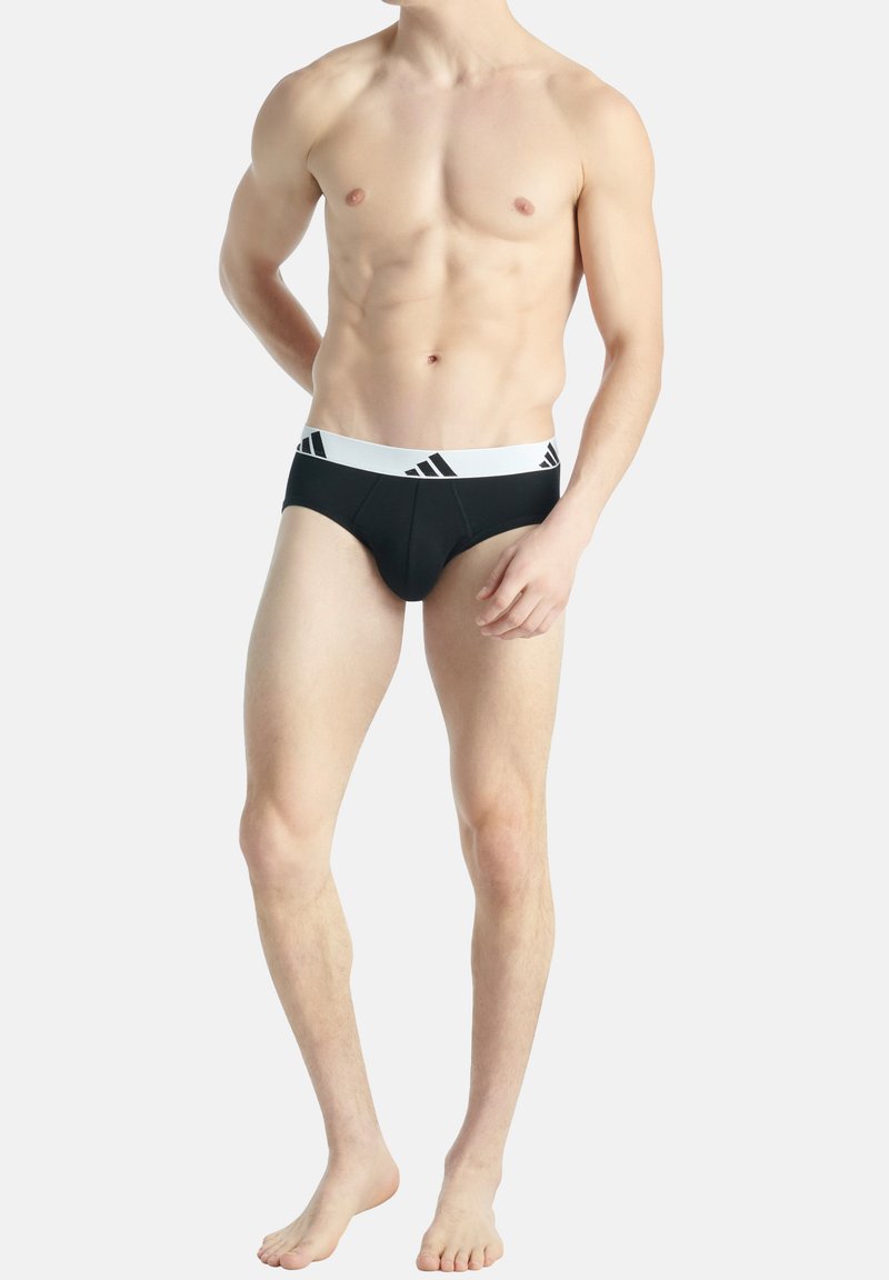 Slip neri da atleta con un elastico bianco e dettagli a tre strisce nere, realizzati in un morbido materiale elasticizzato.