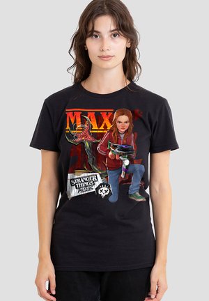 Woman wearing a black t-shirt featuring Max from Stranger Things holding a weapon, with creature and text "Tales from the Upside Down" visible.
