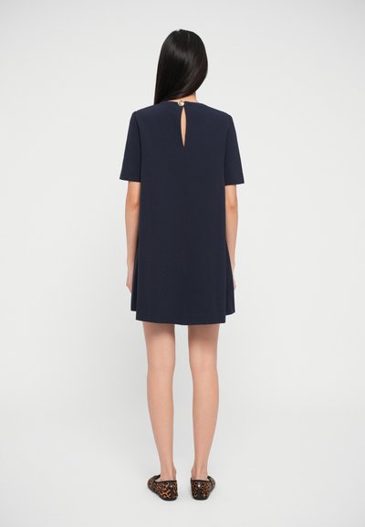 Navy short-sleeve dress with keyhole back detail and round neck. Features a smooth fabric and simple silhouette. Worn with leopard print flats.