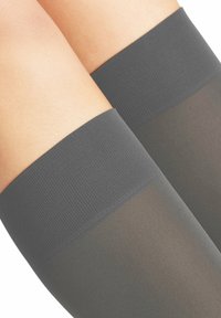 Grijze knie-hoge kousen met een gestructureerde, ribbelige bovenband en glad, transparant materiaal dat tot de tenen reikt.
