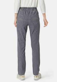 Graue Denim-Hosen mit einem elastischen Bund, zwei Gesäßtaschen mit gestickten Designs und geradem Bein. Strukturierter, lässiger Stil.