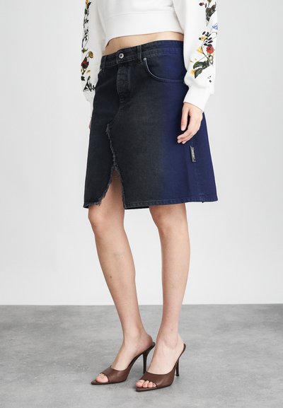 Jupe en denim avec une teinte foncée, un ourlet effiloché et une fente frontale asymétrique. Assortie à des mules à talons bruns et un sweat-shirt floral blanc.