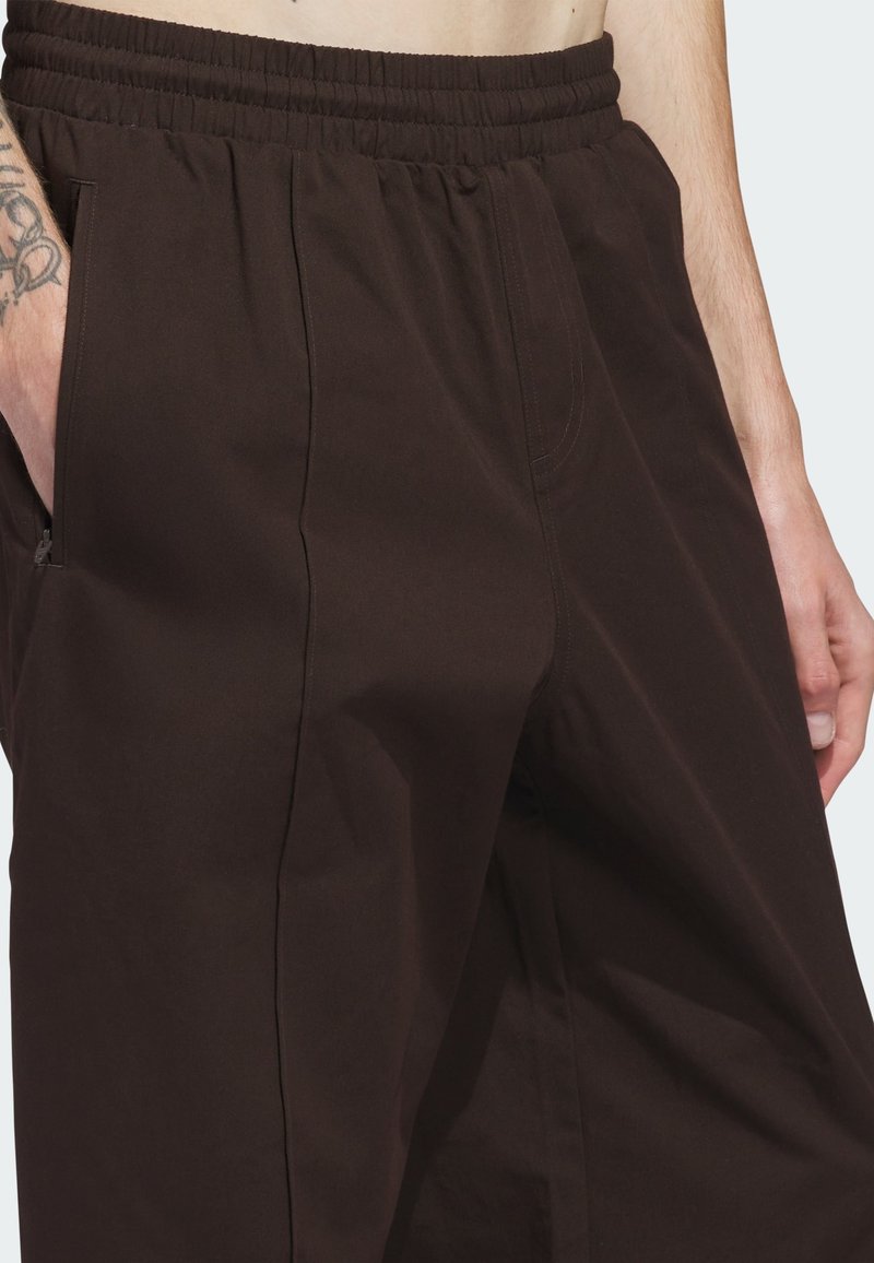 Pantaloni jogger in cotone marrone con vita elastica, tasche laterali e vestibilità comoda. Tessuto liscio con dettagli di cuciture minime.